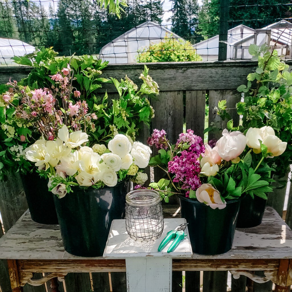 Buckets of white and lilac flowers with foliage on a table ready to be designed.ready to be des 