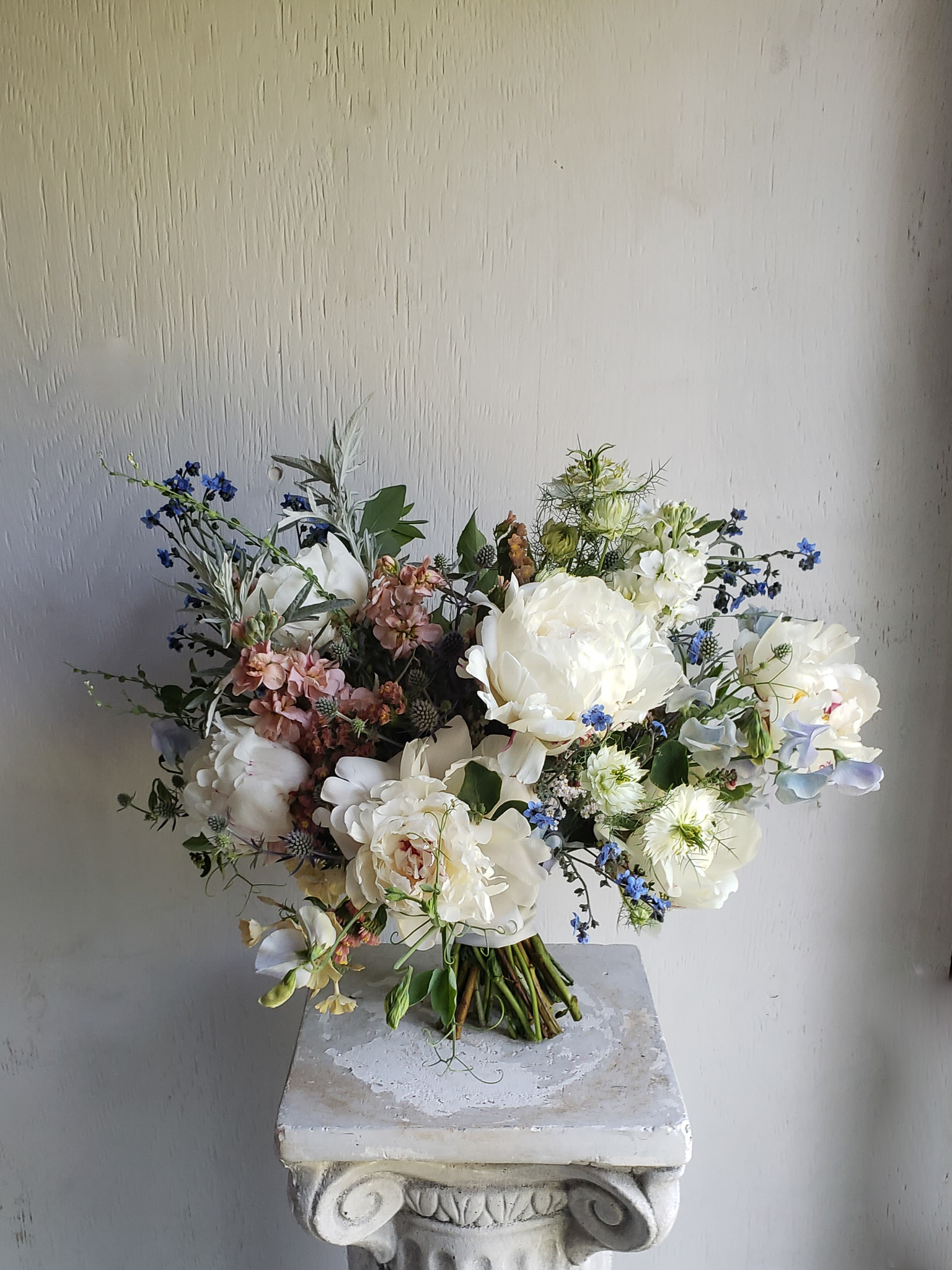 A soft, spring bridal bouquet with peonies and other spring flowers.